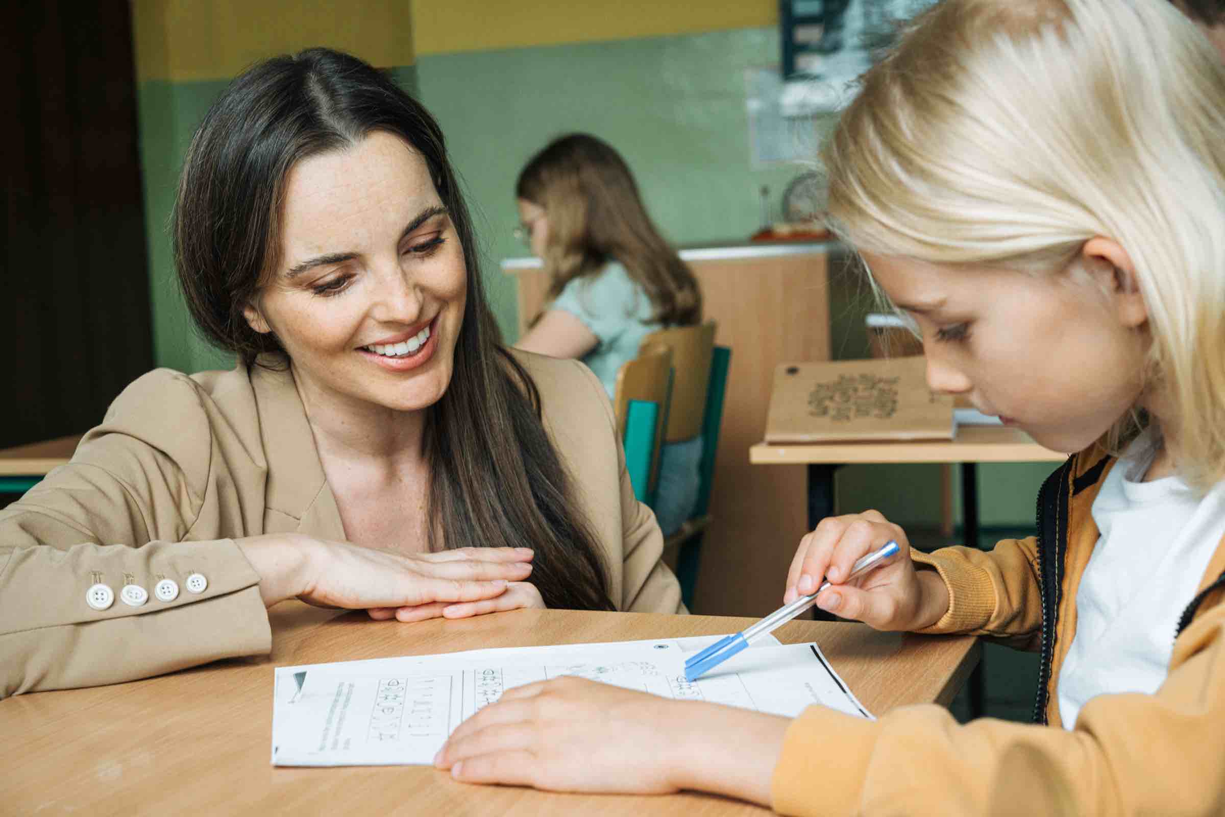 Smiling teacher listening to student's doubts while teaching him in classroom