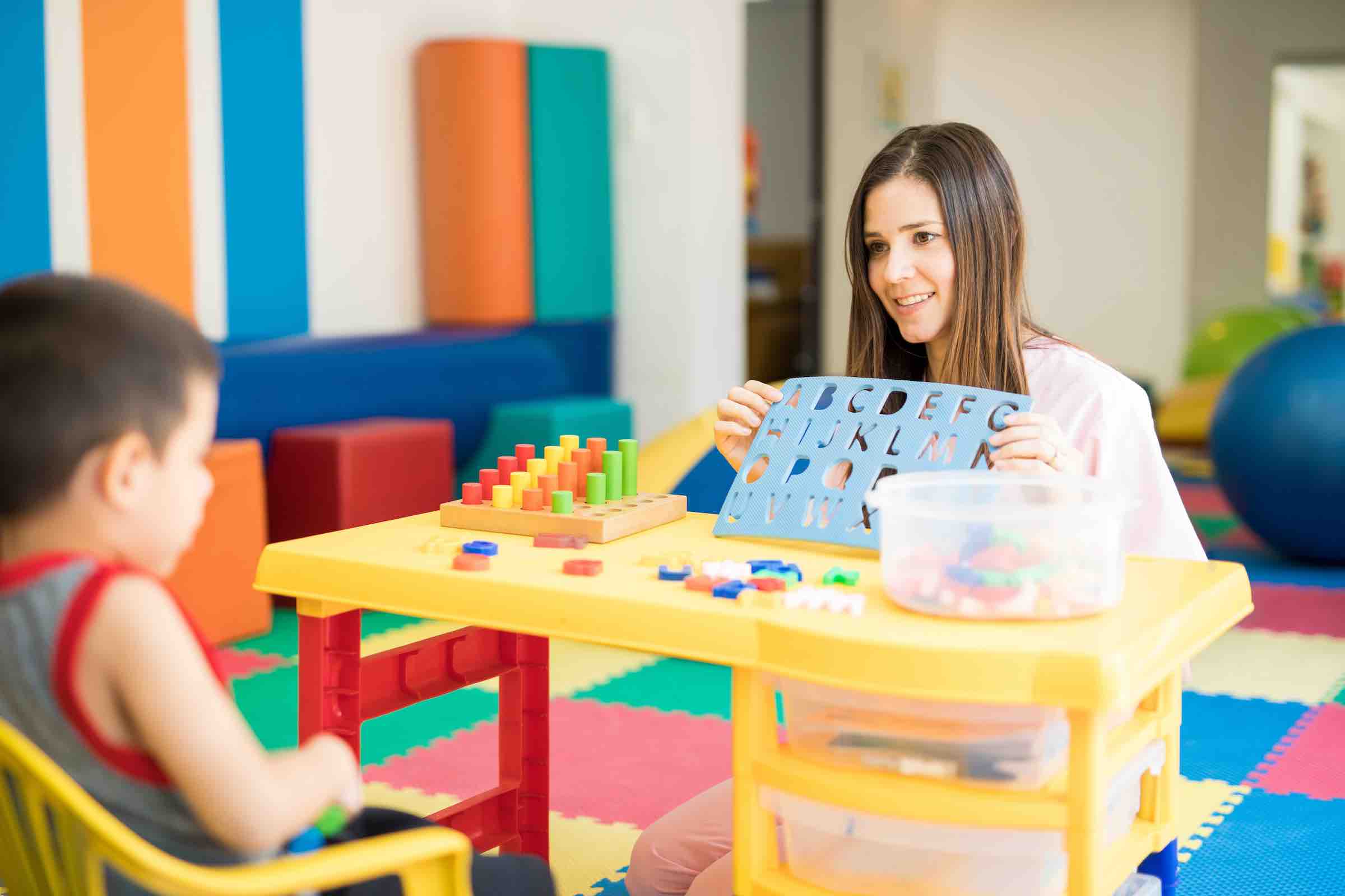Portrait of a beautiful female language therapist working and practicing the alphabet with a kid