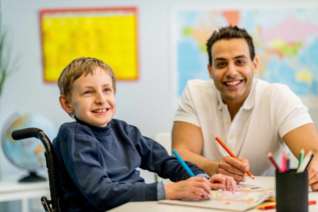 Child in wheelchair with counselor at school table