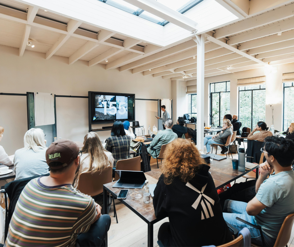Group of adults sitting in a room listening to a speaker