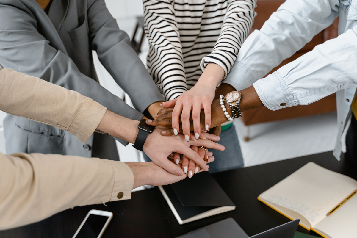 Group of people standing together with their hands on top of each other in a circle