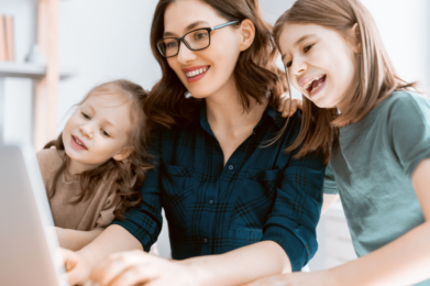 Mom sitting at a computer with a child on her left and right both looking at the computer