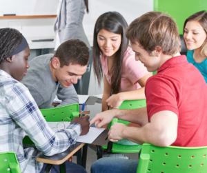 Group of five young adults sitting around a table working together