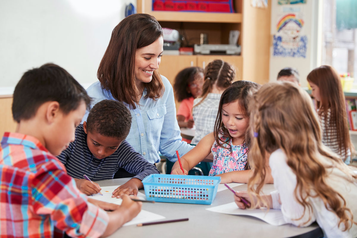 Teacher with students drawing at table