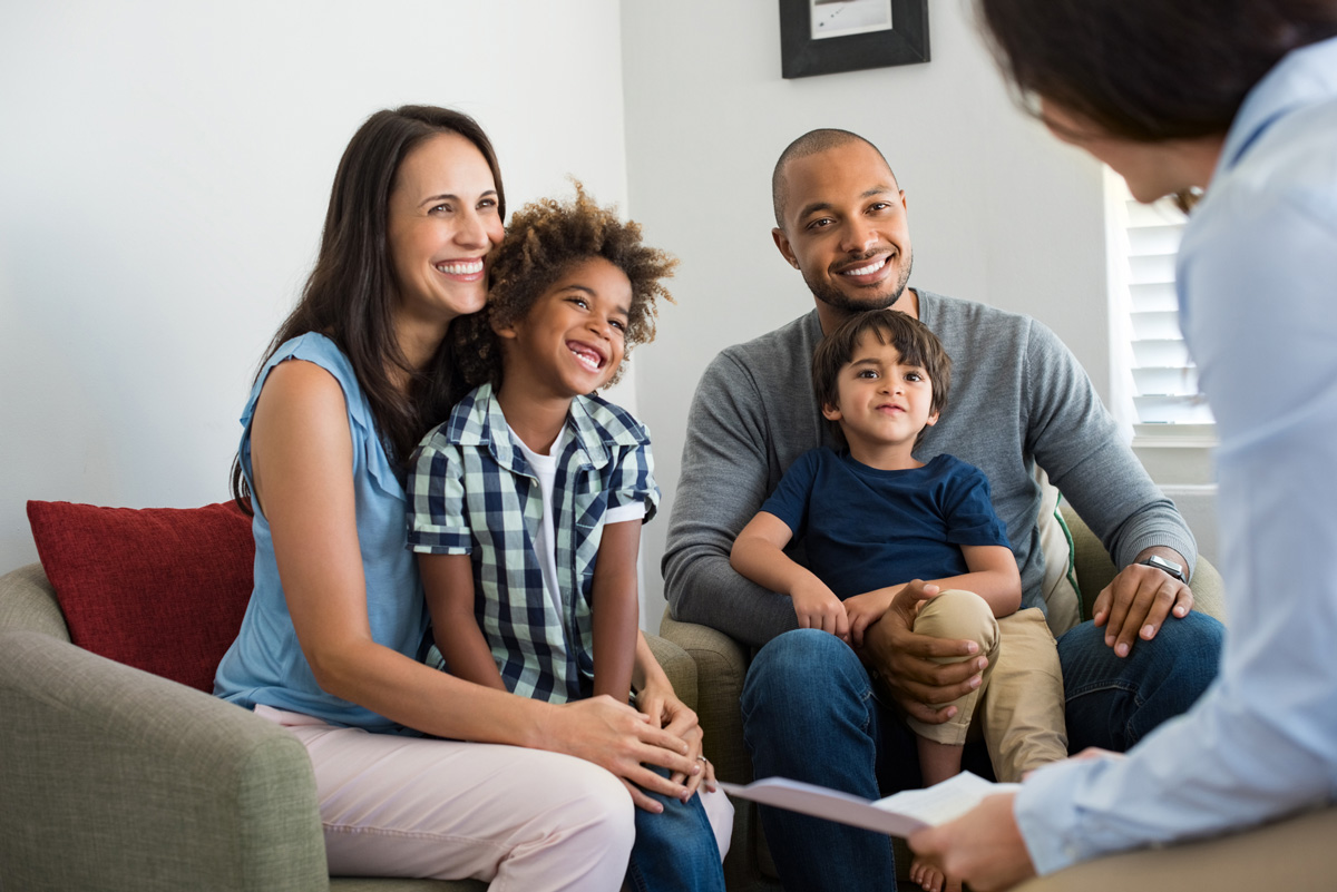 Image of mother, father and two sons smiling during a meeting