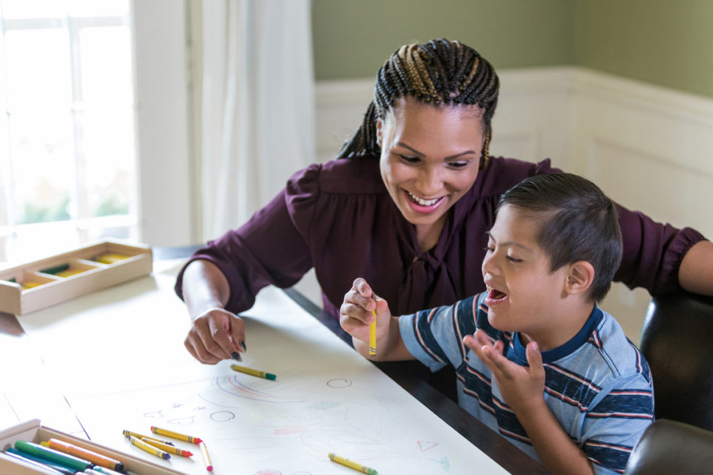 Image of young boy coloring next to a service provider