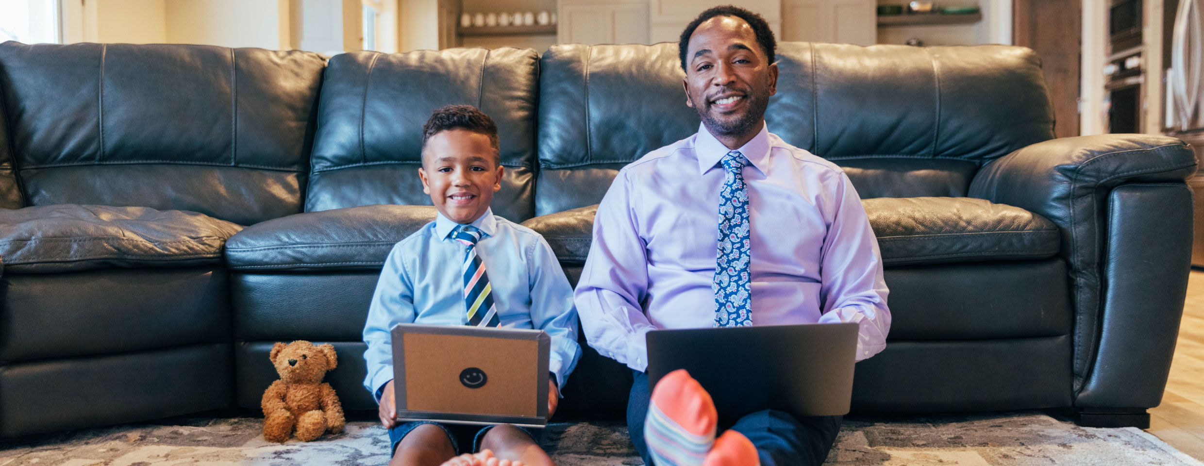 father and son with laptops, smiling, colorful socks