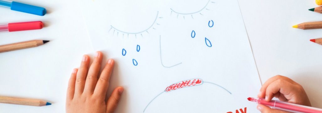 Image of child hands drawing sad face