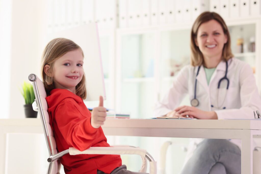 girl giving thumbs up, next to doctor