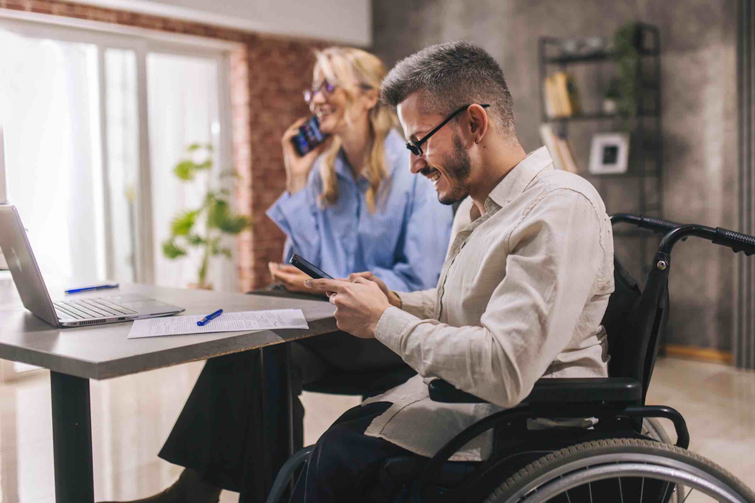 young businessman in wheelchair having discussion with his female colleague in the board room.
