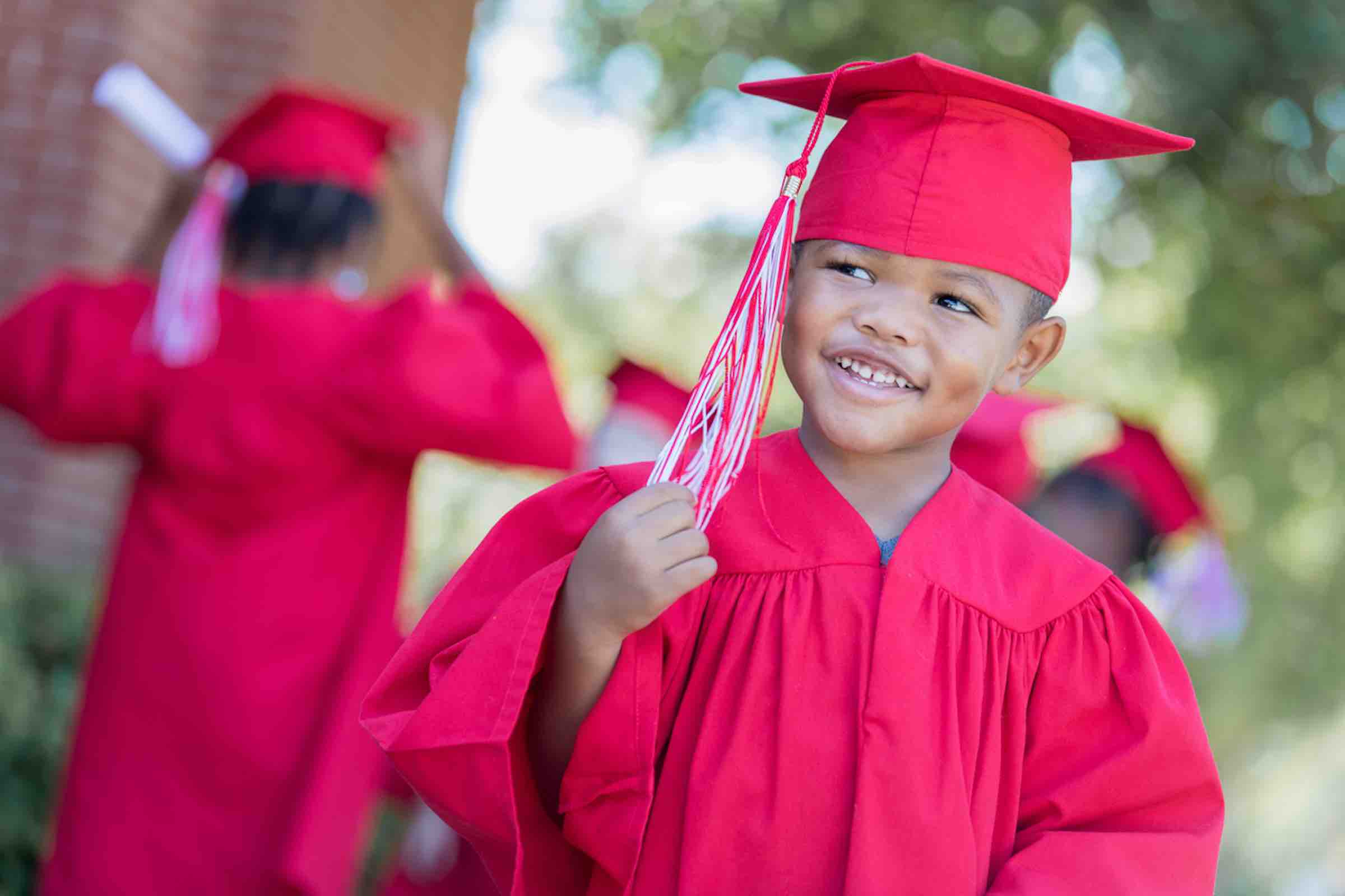 kindergarten student in graduation cap and gown, smiling