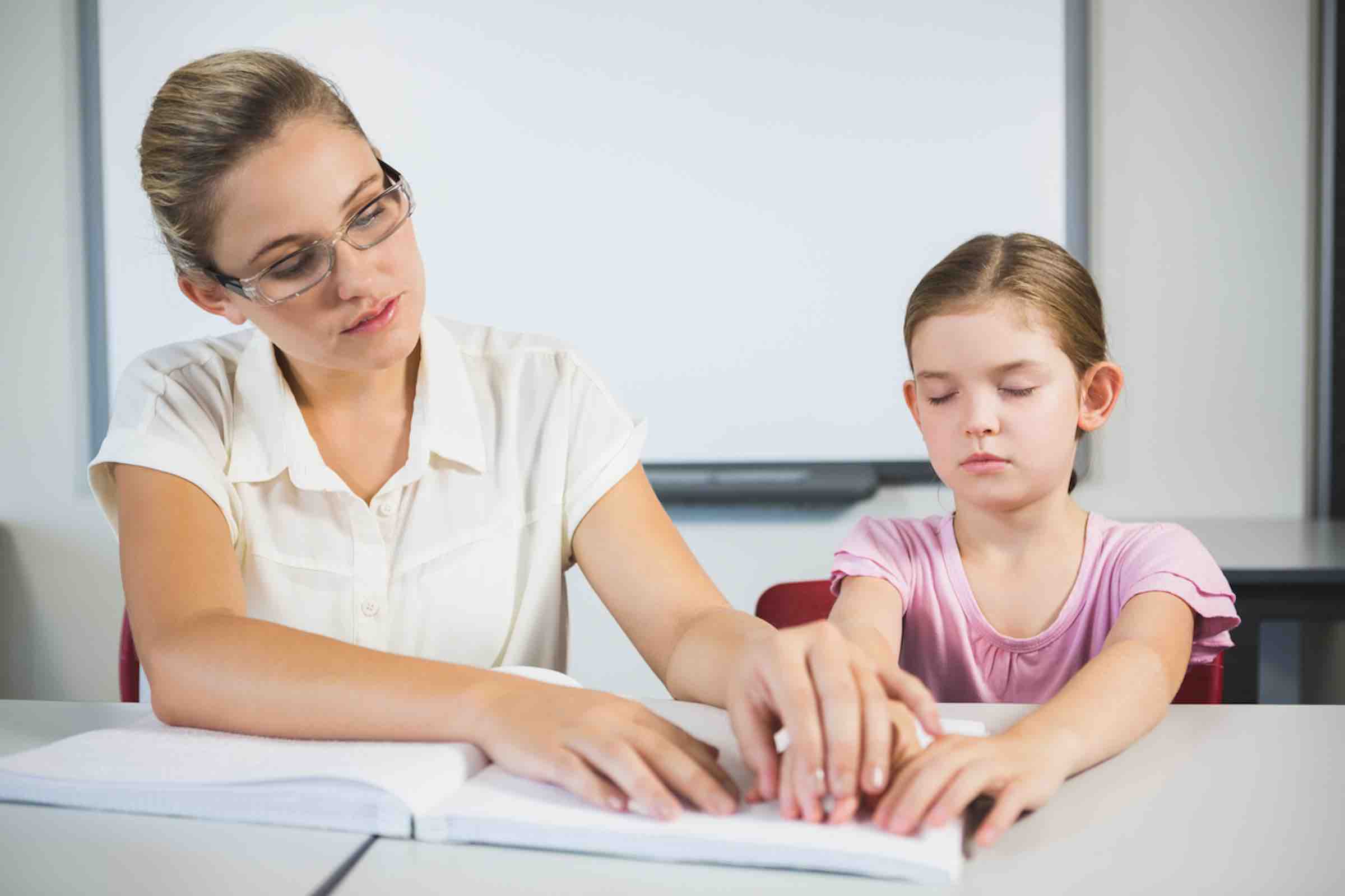 visually impaired female student reading with teacher